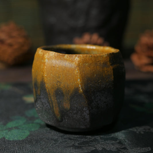 Close-up of the natural amber-colored kiln-fired glaze on a dark iron clay tea cup.