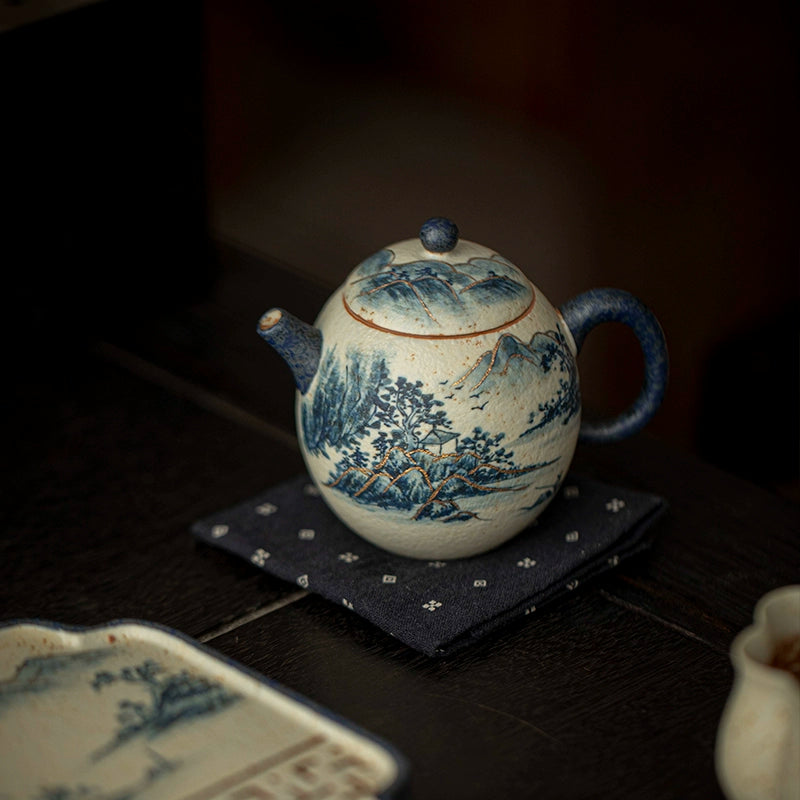 Gold accents trace the mountain ridges, while shades of blue dance across the porcelain surface. This teapot embodies the elegance of traditional craftsmanship and modern refinement.