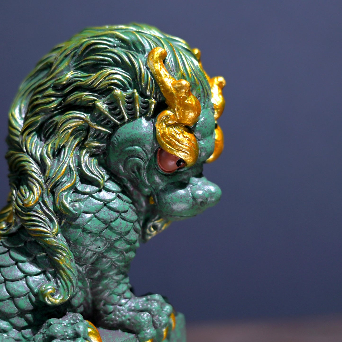 Intricately sculpted dragon tea pet in green stone with gold detailing for tea table display.