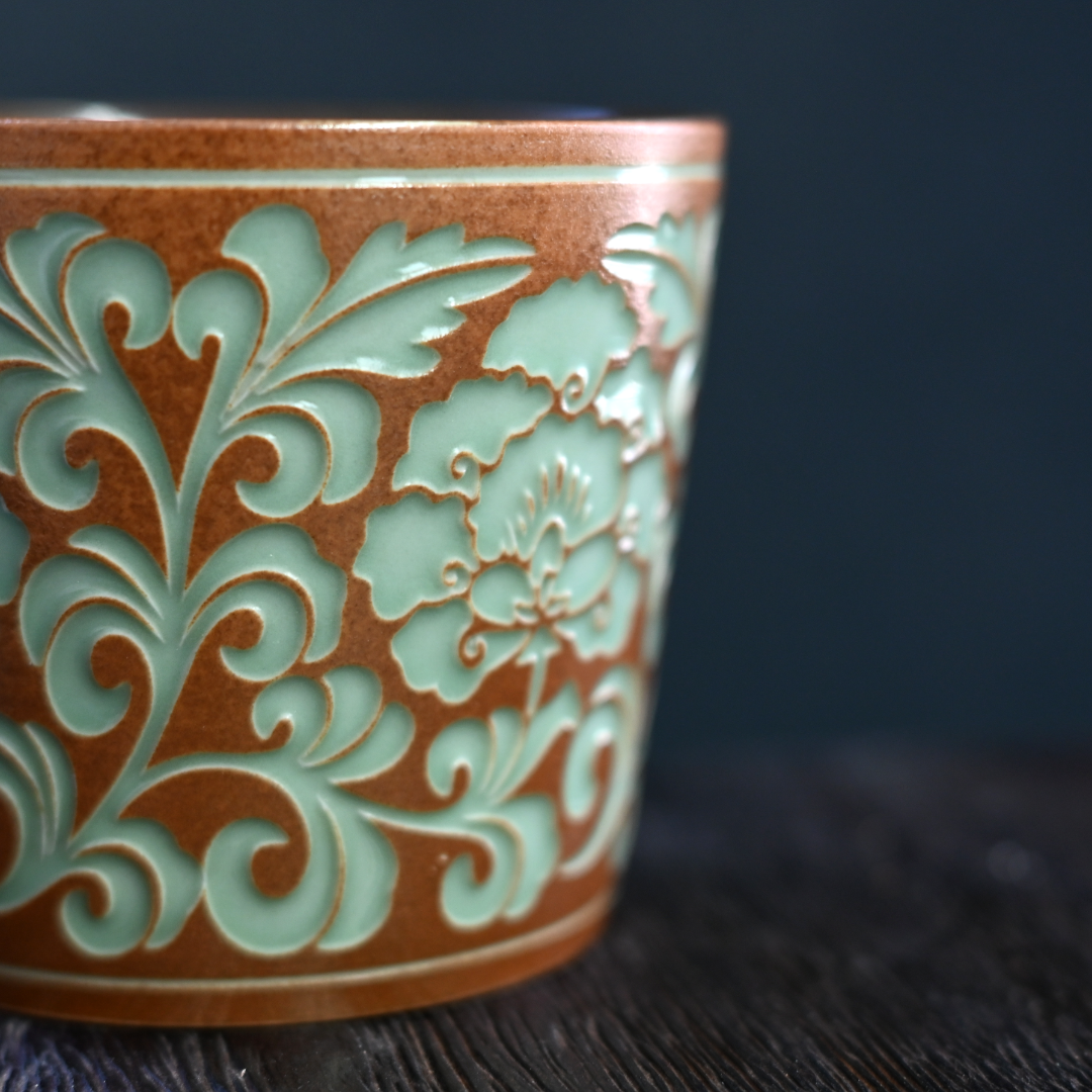 Contemporary large celadon mug with traditional plant ash glaze and peony carvings, made in Longquan for daily tea/coffee use.