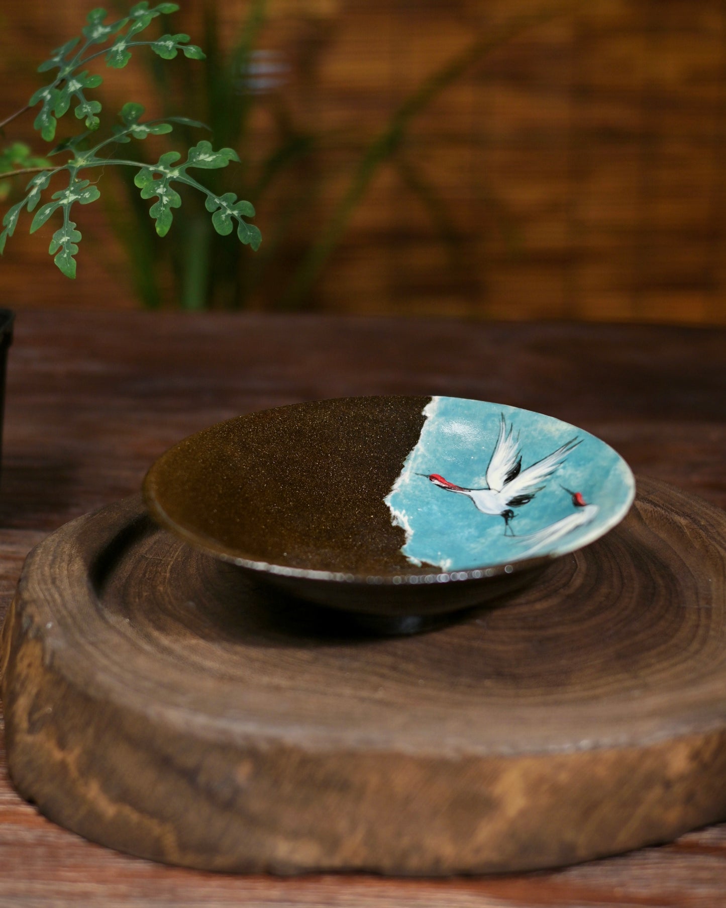 Angled view of the teapot drip tray, highlighting its textured, coarse pottery base and elegant form.