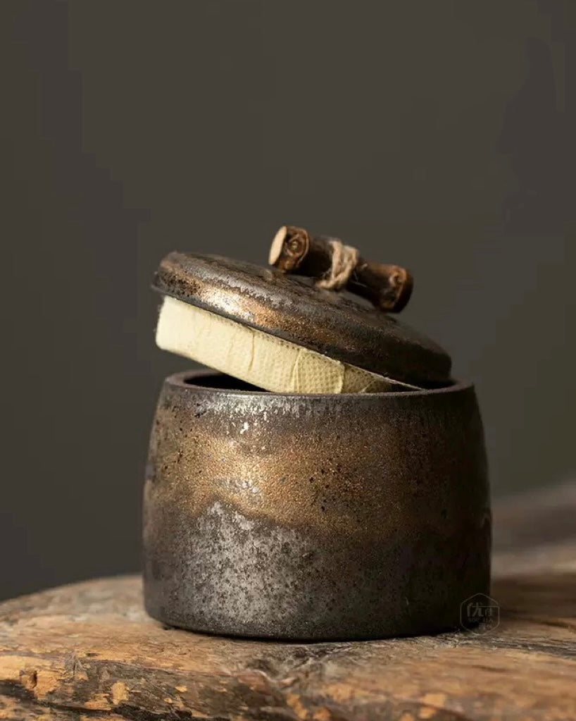 Side view of a vintage gilded stoneware tea container for loose leaf tea.