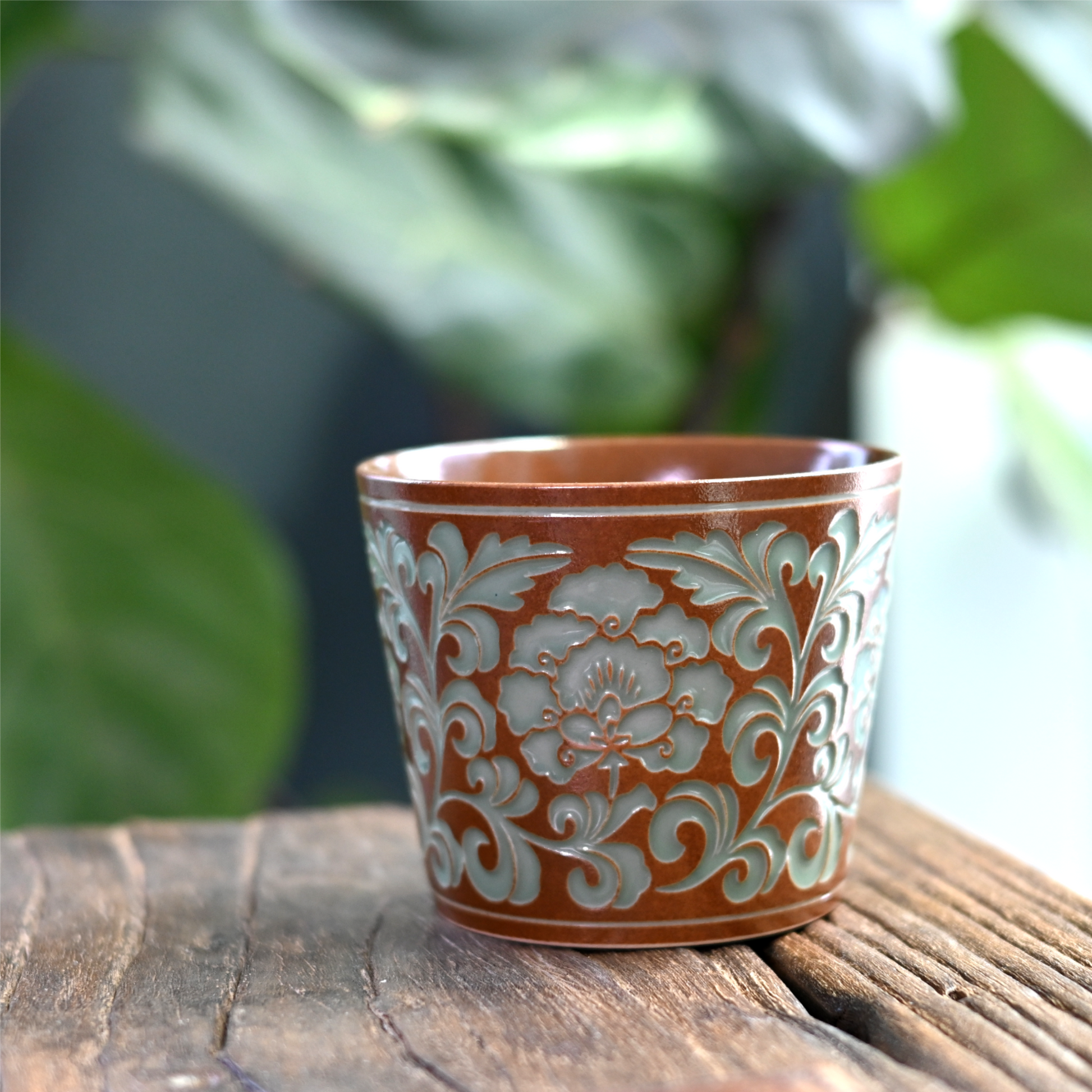 Plant ash glazed Longquan celadon mug featuring carved peony relief for grip, combining traditional plum green glaze with modern functionality.