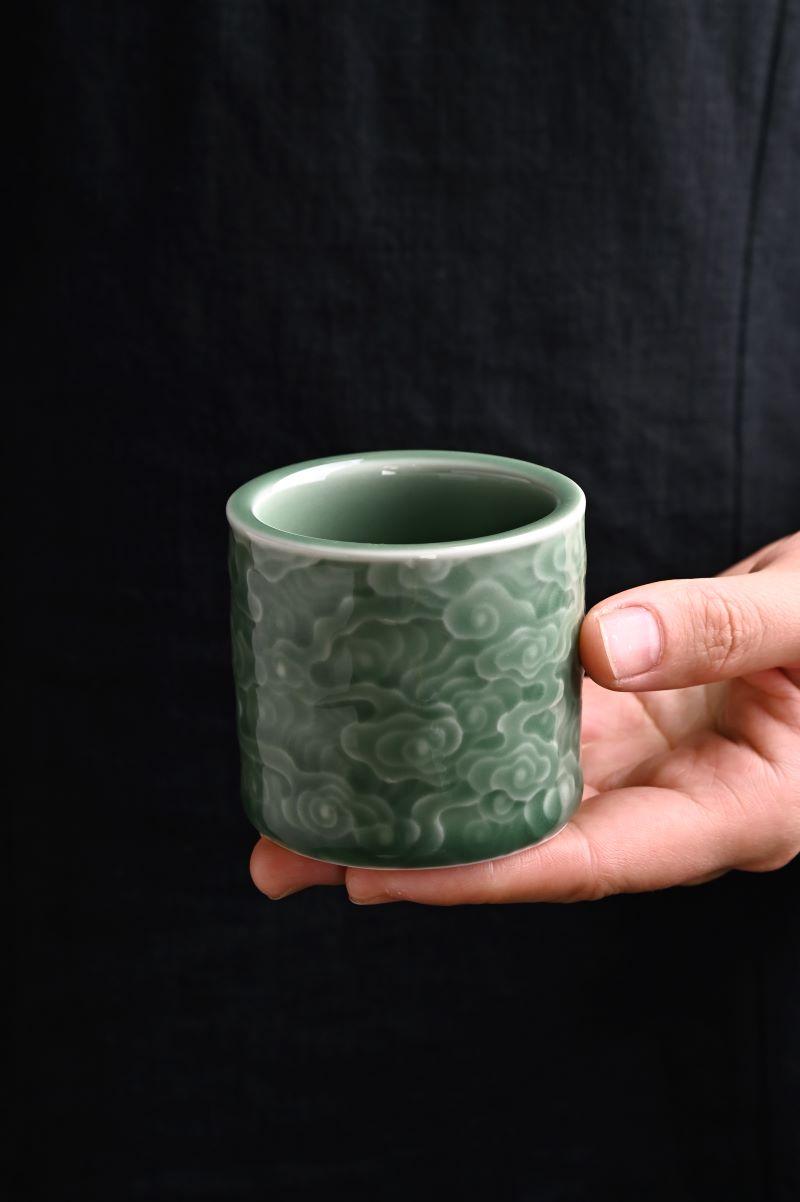 Handcrafted Longquan Celadon Cup featuring elegant cloud relief in plum green glaze.