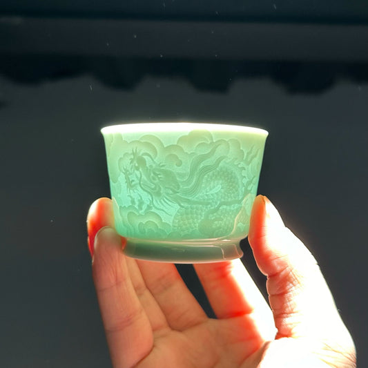 Backlit view showing the light-transmitting quality of the translucent Longquan Celadon relief carved tea cup.