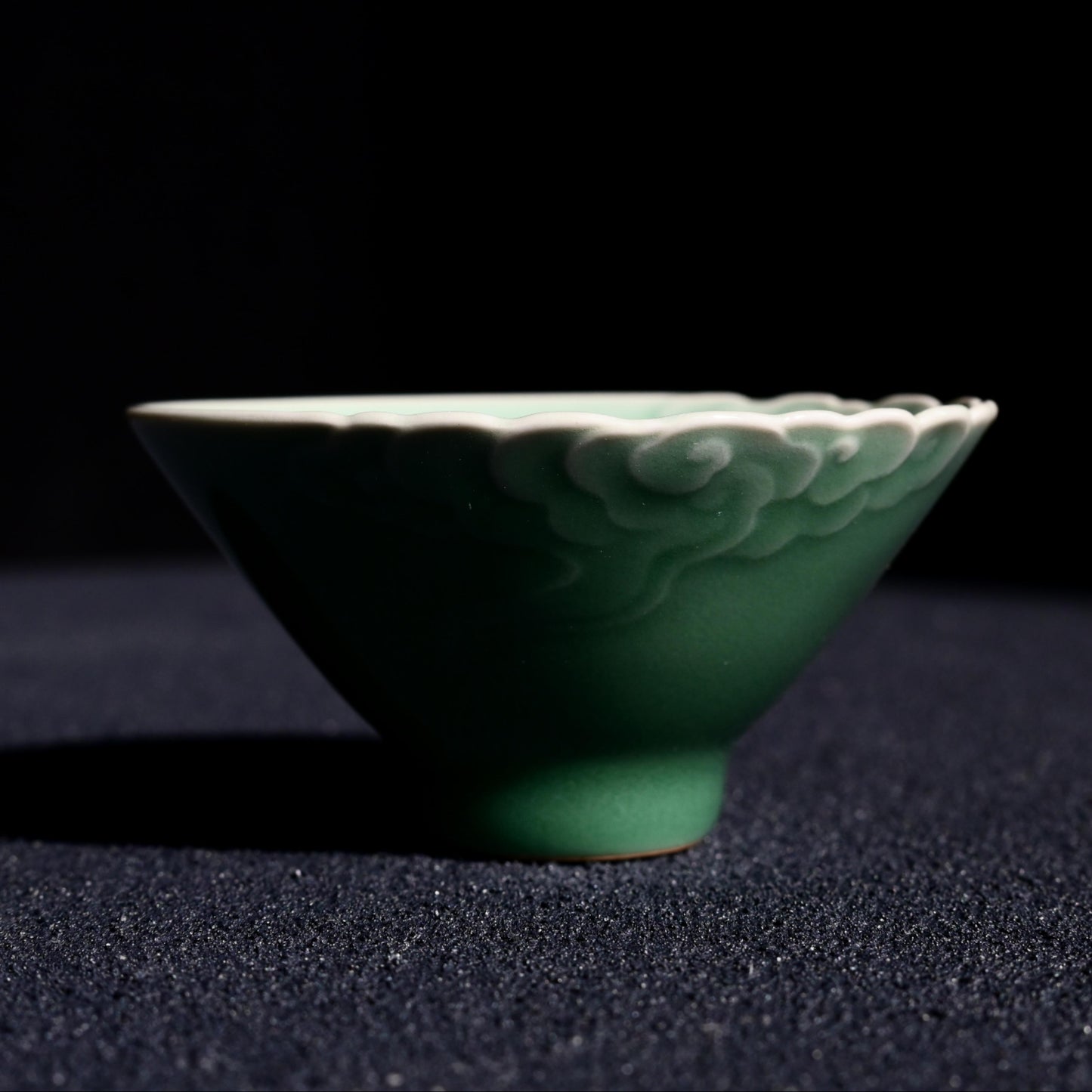 Tea ceremony cup with raised auspicious clouds design, finished in authentic Longquan plum green celadon glaze
