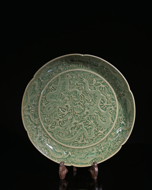 Northern Song dynasty carved celadon dish showing deep three-dimensional dragon relief under olive glaze