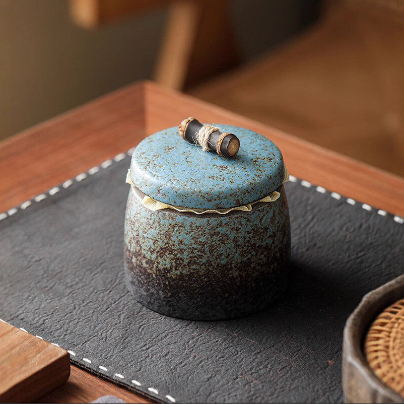 Minimalist setup featuring a gilded vintage Chinese stoneware tea caddy on a wooden table.