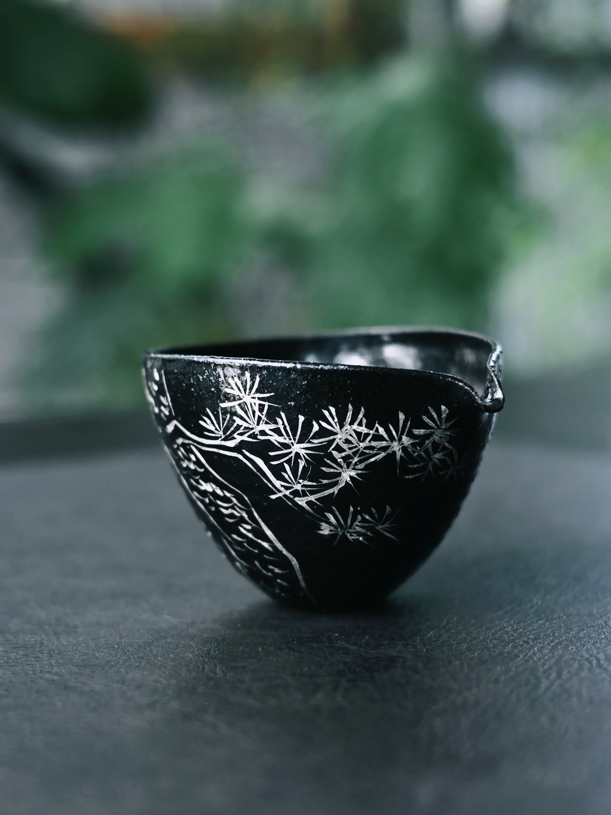 Japanese wabi-sabi tea ware set: glossy black surface with silver calligraphy and pine symbolism, celebrating transience and imperfection in zen tea practice.