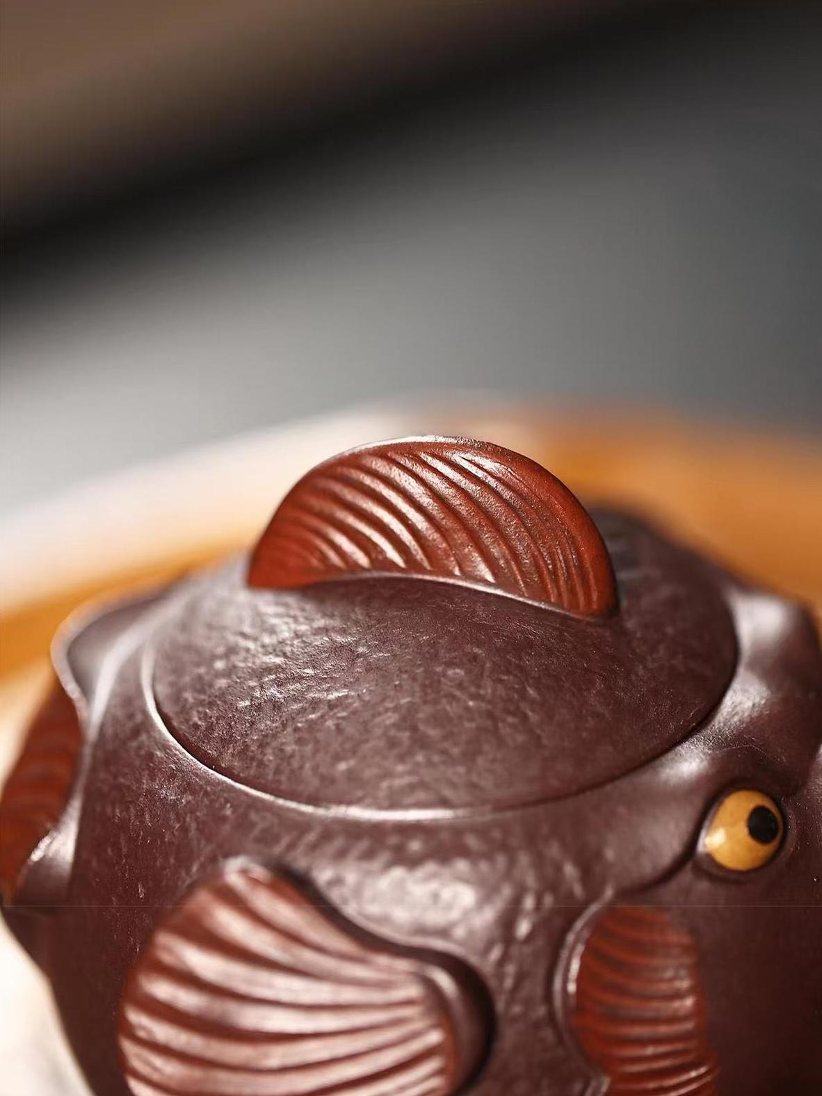 Intricately hand-sculpted pufferfish teapot with textured skin patterns and cheerful expression, combining art with practical tea functionality.
