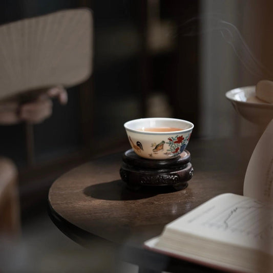 A small Ming Dynasty Chenghua doucai chicken cup, its body painted with a rooster and hen leading chicks as they forage and play, less than 8 cm in diameter
