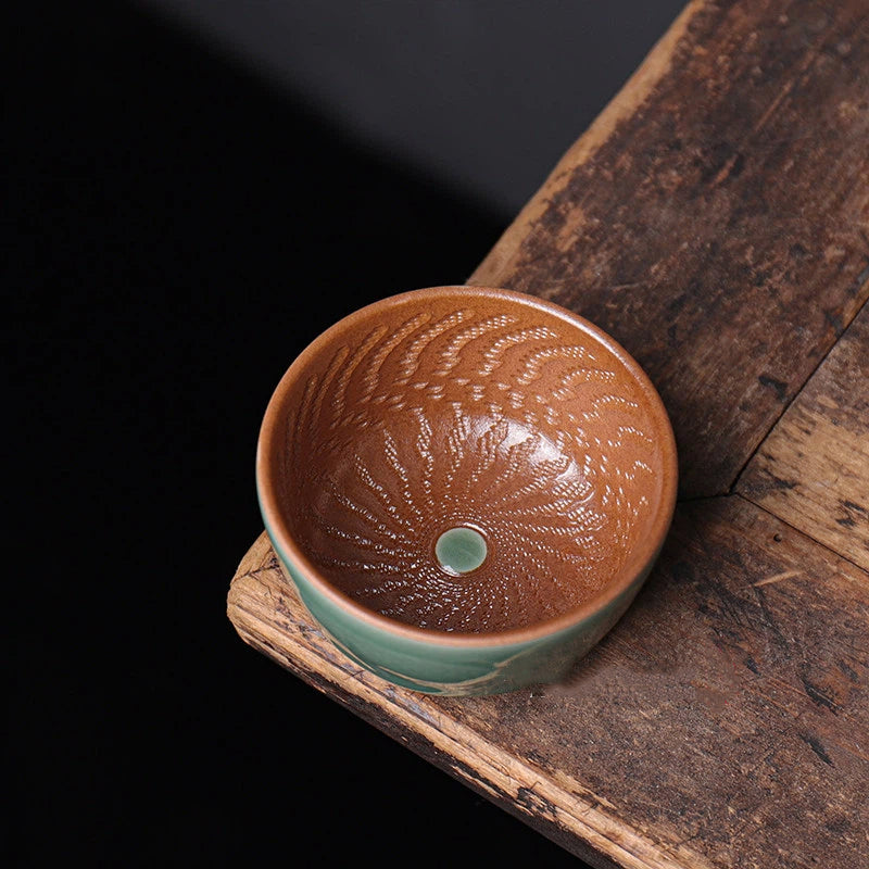 Detailed shot of the hand-carved chattered pattern inside a Longquan Celadon cup, highlighting the wood ash finish.
