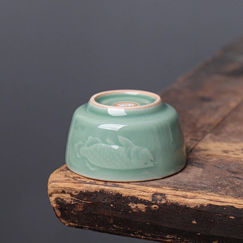 Handmade celadon teacup with iron-rich clay accents on the rim, showcasing the "Dragon-Fish" leap motif.