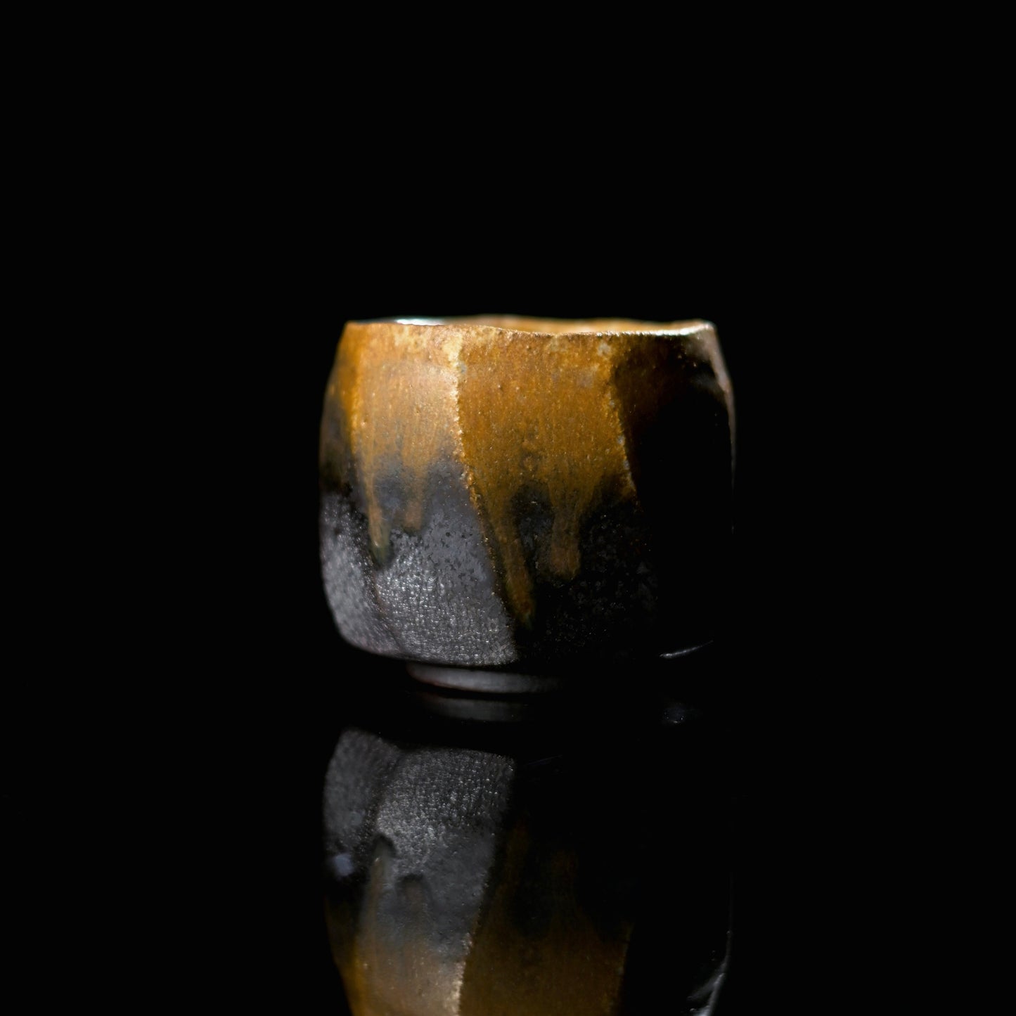 Unique handmade wood-fired iron-bodied teacup with a dramatic golden ash glaze drip.