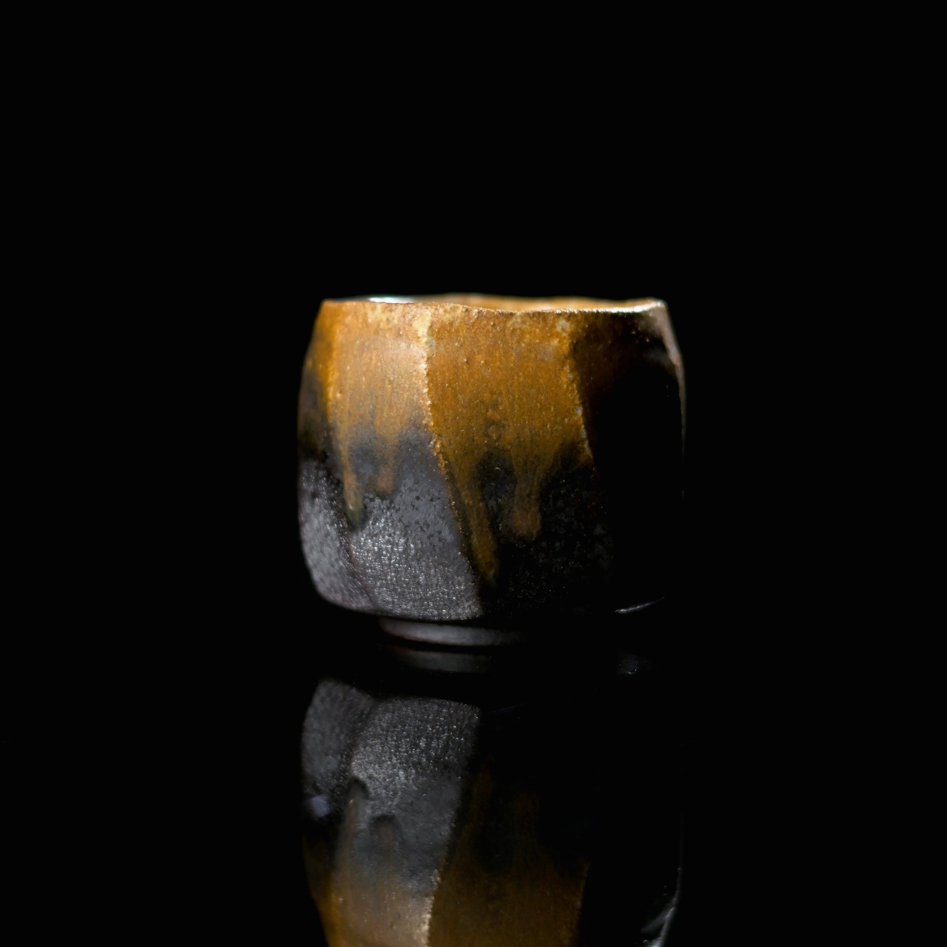 Unique handmade wood-fired iron-bodied teacup with a dramatic golden ash glaze drip.