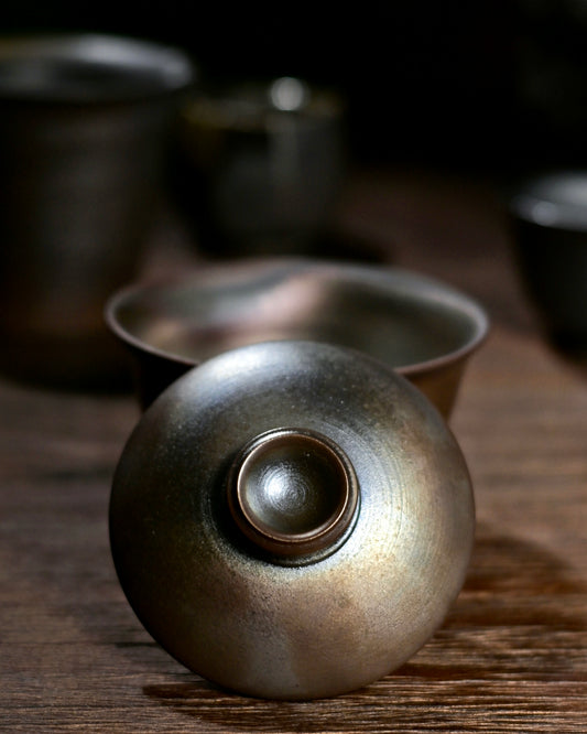 Close-up of the metallic luster and rustic texture of a wood-fired iron clay tea vessel