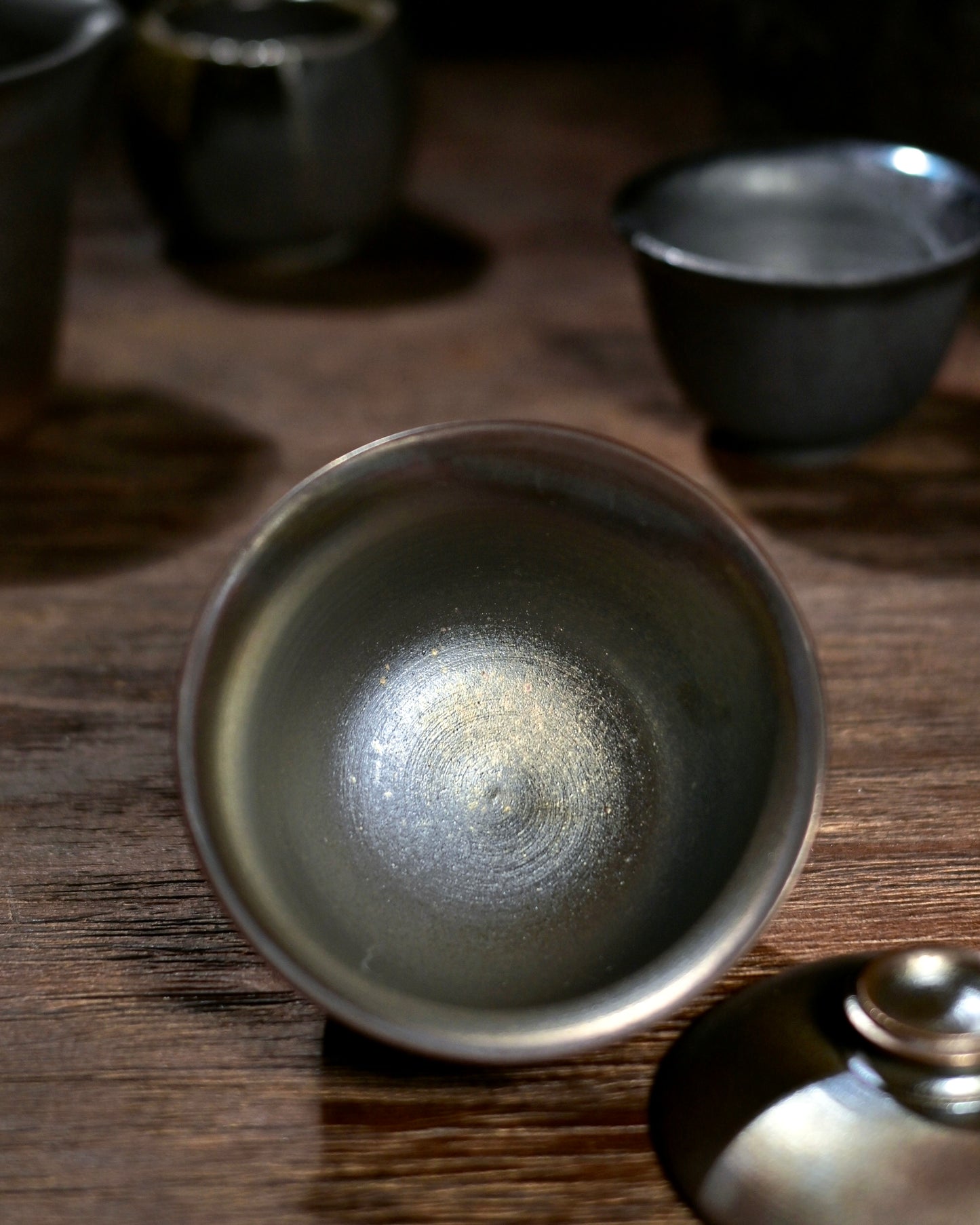 The flared rim and rustic brown finish of a handmade wood-fired stoneware Gaiwan.