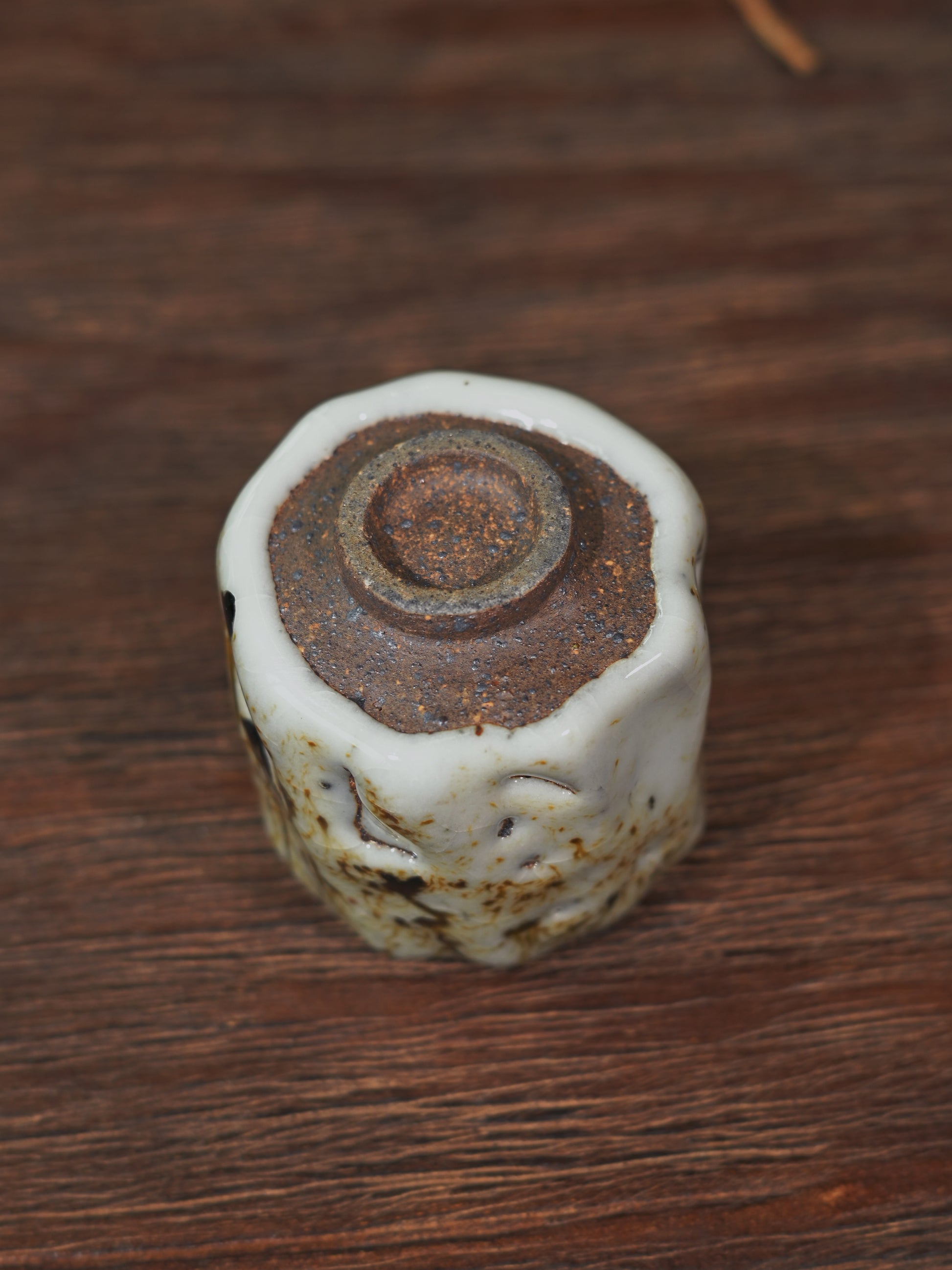 Artisan Shino teacup "Ashes Bloom" against a soft bokeh background with a traditional teapot.