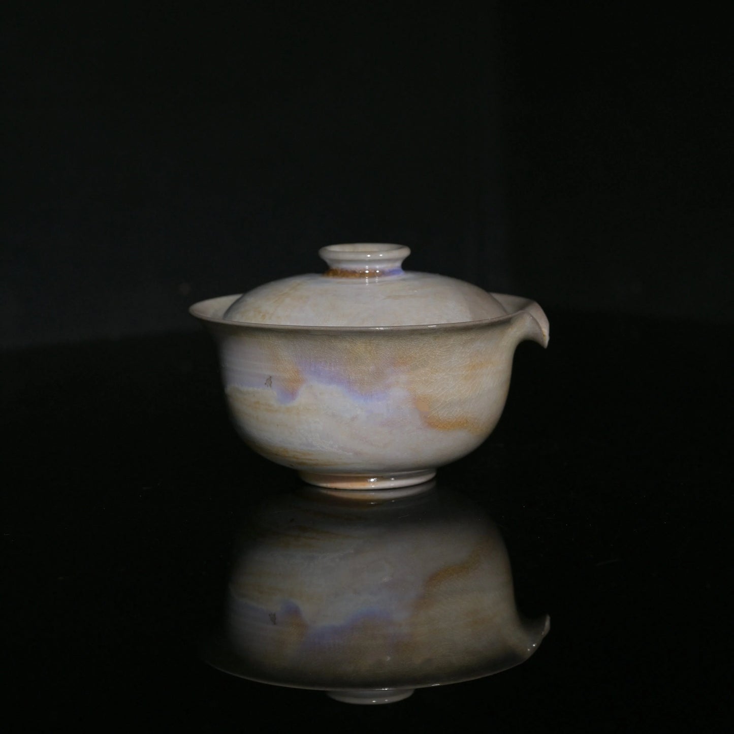 Close-up of the pearlescent lavender and gold kiln-change patterns on a handmade Gaiwan.