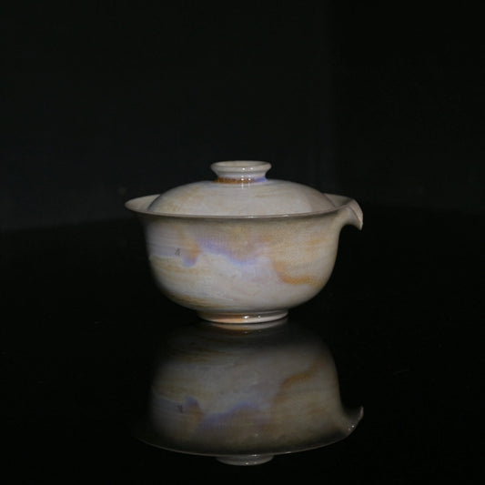 Close-up of the pearlescent lavender and gold kiln-change patterns on a handmade Gaiwan.