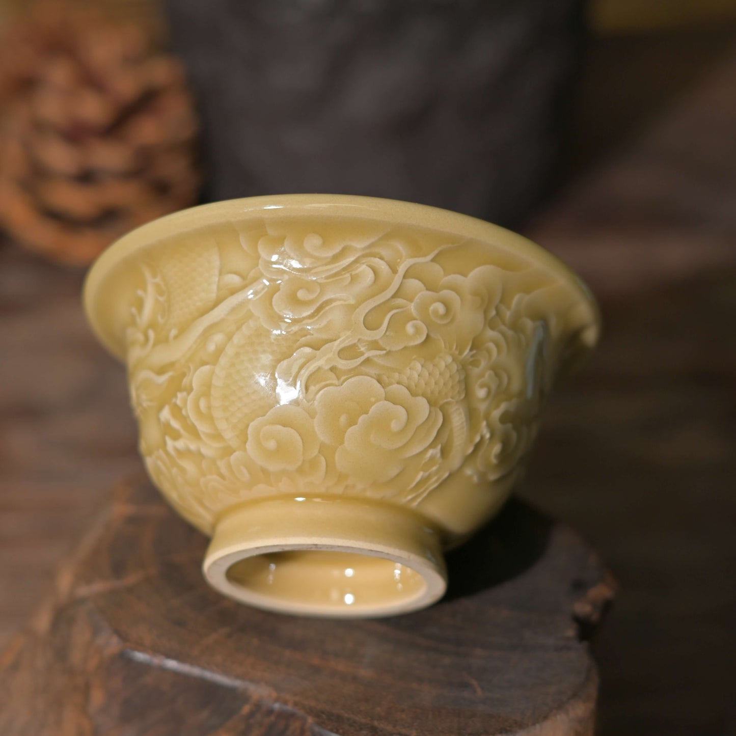 The Imperial Longquan Celadon Dragon Cup with rare Golden Glaze sitting on a black reflective surface.