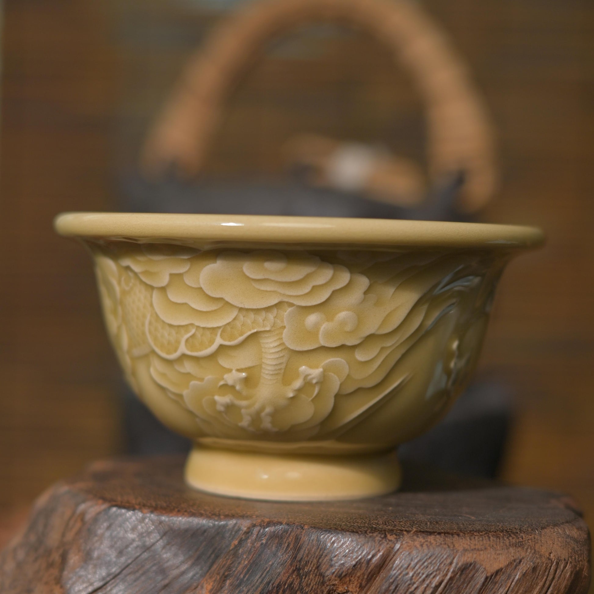 Luxury authentic Longquan Celadon stoneware tea cup with yellow glaze and hand-carved dragon motif on a dark green backdrop.