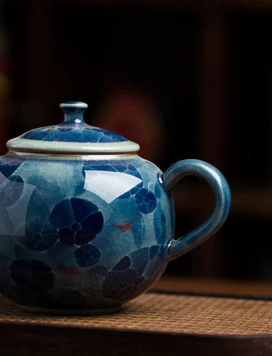 Detailed view of hand-painted lotus flowers and leaves on a premium Chinese porcelain teapot.