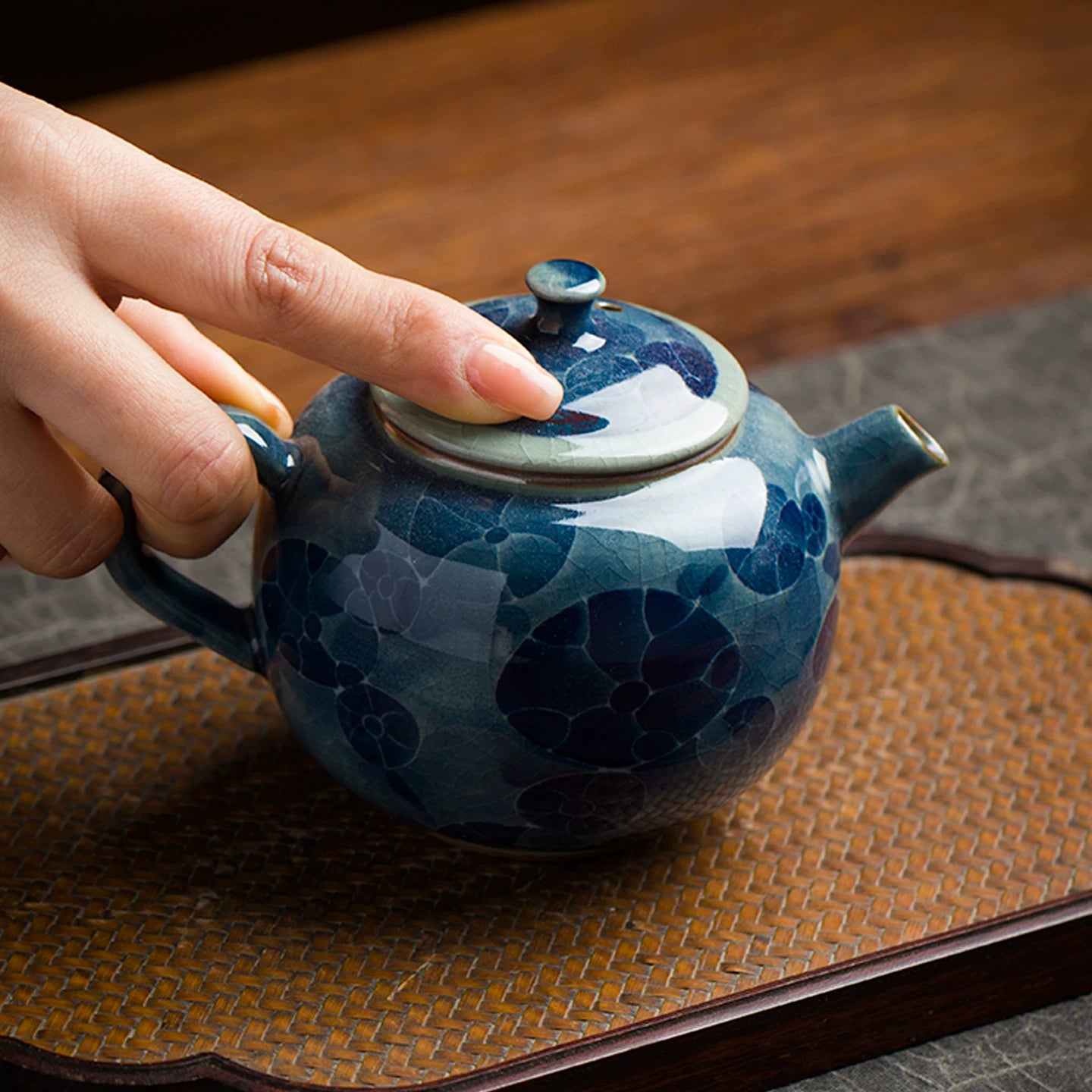 Close-up of the fine crackle glaze and cobalt blue pigments on a handmade floral porcelain vessel.