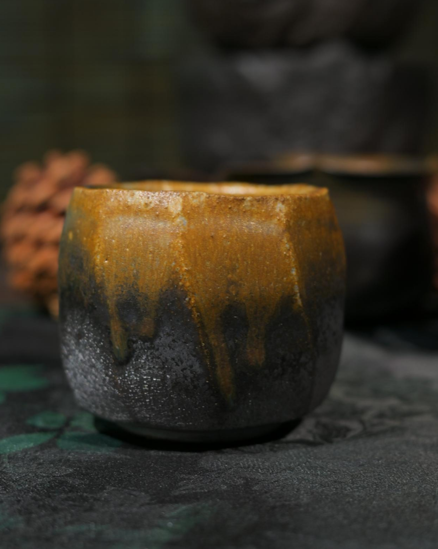 Artisan iron-bodied tea bowl with natural wood-ash "tears" glaze, front view.