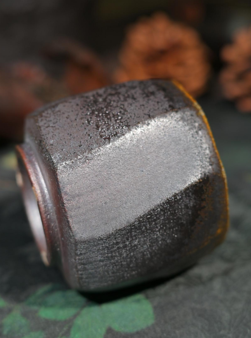 Collector's edition wood-fired teacup with scorched earth texture and golden mineral flow.