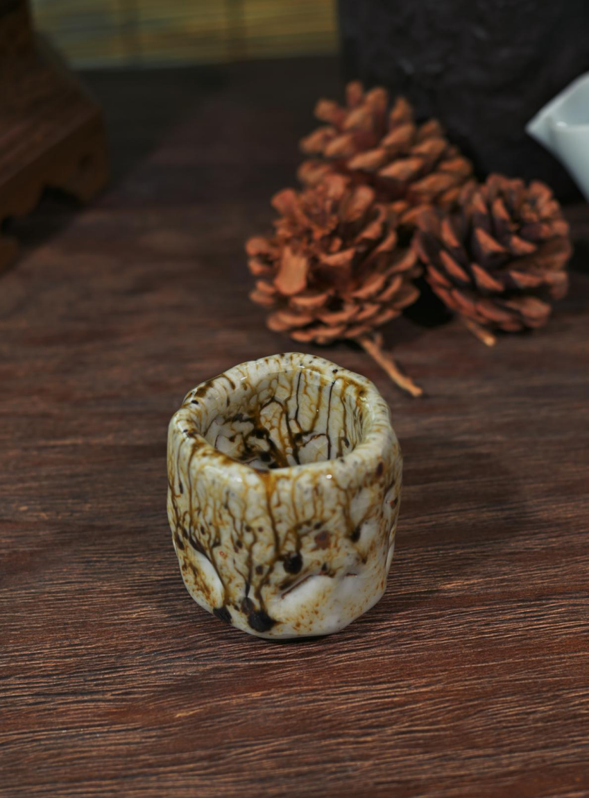 A singular Wabi-Sabi tea cup with thick crackle glaze and rustic earthy mineral bursts.