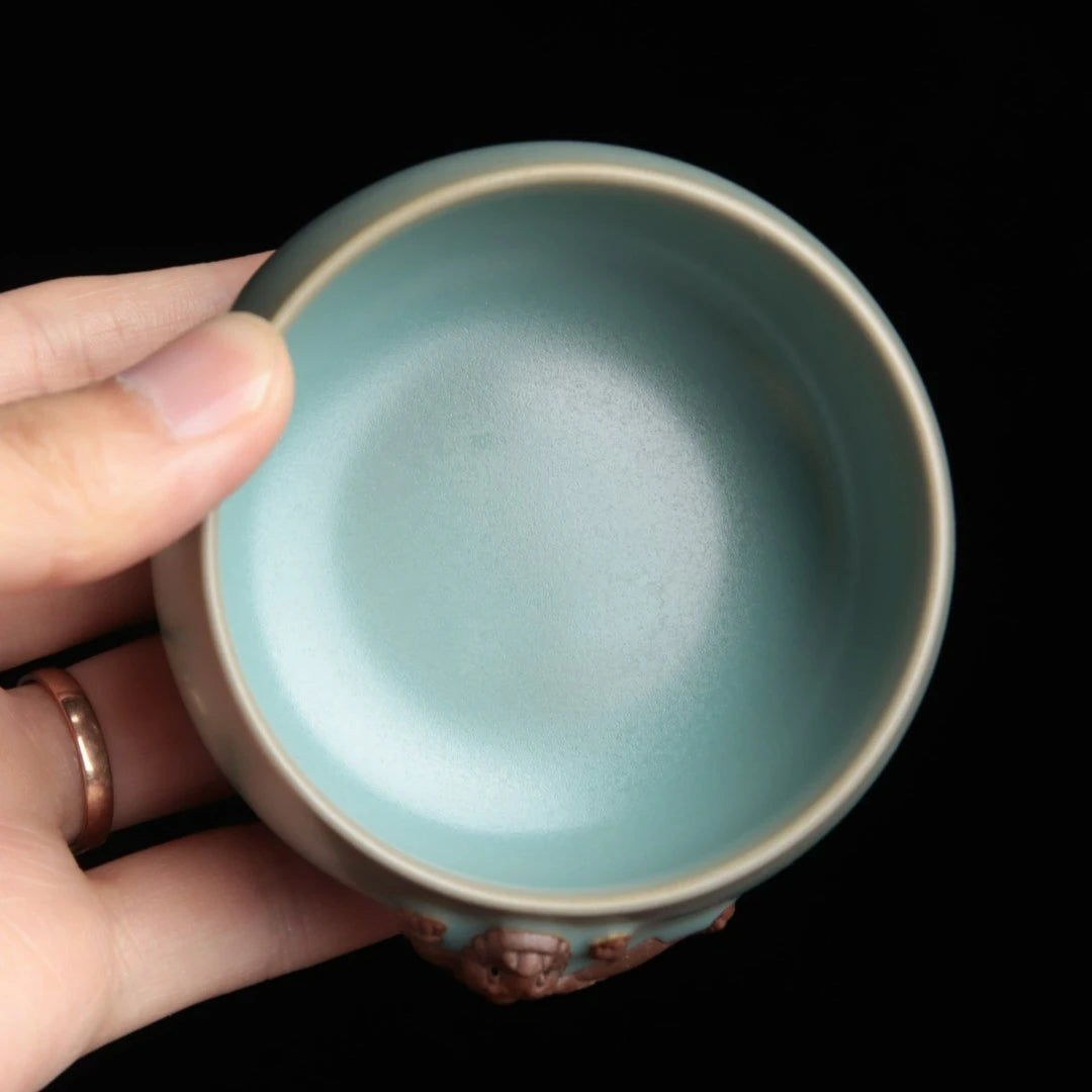 An elegant 120ml Chinese master teacup held in a hand showing texture contrast.