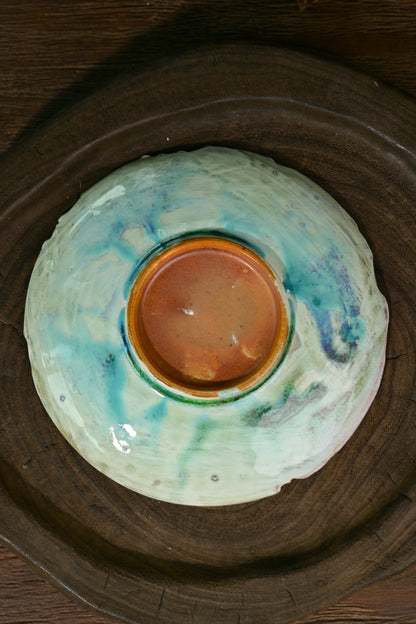 Close-up of soda kiln turquoise glaze melt and organic Wabi-sabi rim on artisan ceramic saucer