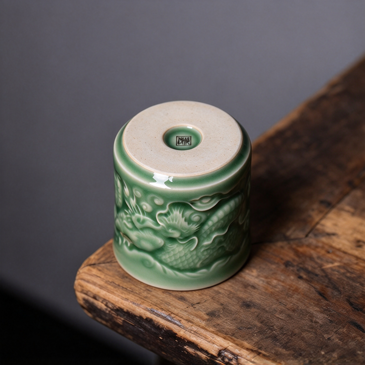 Detailed view of celadon glaze pooling over hand-carved dragon scales on porcelain cup