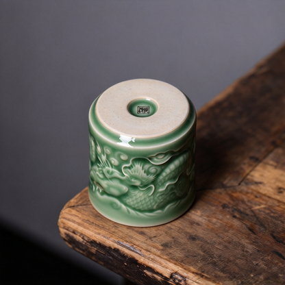Detailed view of celadon glaze pooling over hand-carved dragon scales on porcelain cup