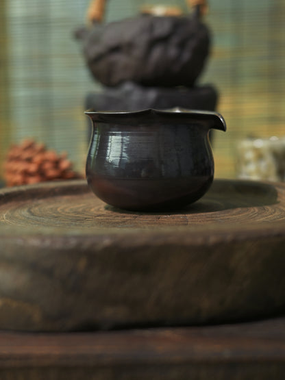 Hand-shaped iron clay fairness cup with a deep metallic luster for professional tea tasting.