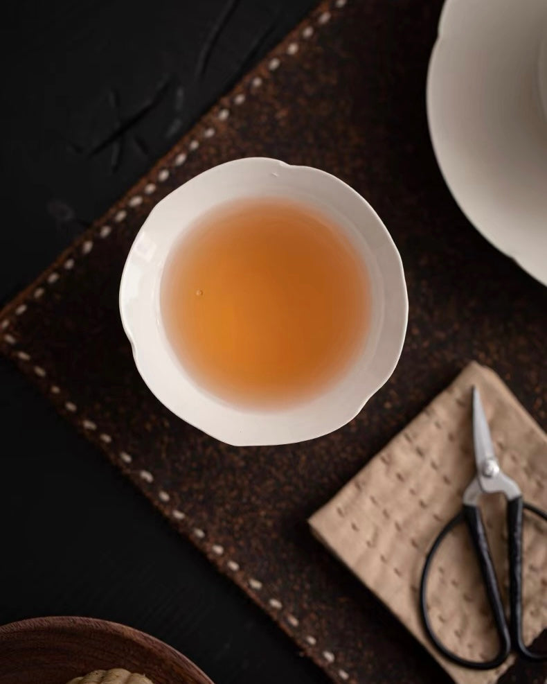 Ash-glazed teacup with petal-inspired rim, combining ergonomic design with botanical artistry