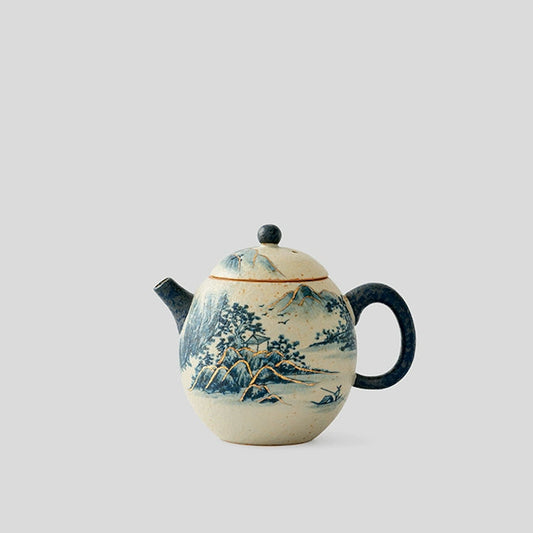 Each Blue and White Porcelain Teapot is hand-painted by skilled artisans, depicting tranquil mountains and flowing rivers in soft cobalt hues. The gilt-lined contours shimmer under the light, reflecting both tradition and elegance.