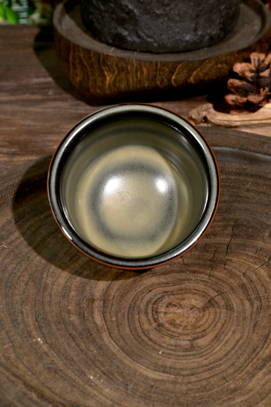 Handcrafted 120ml Chinese celadon master cup displaying tea-dust mineral glaze transmutation