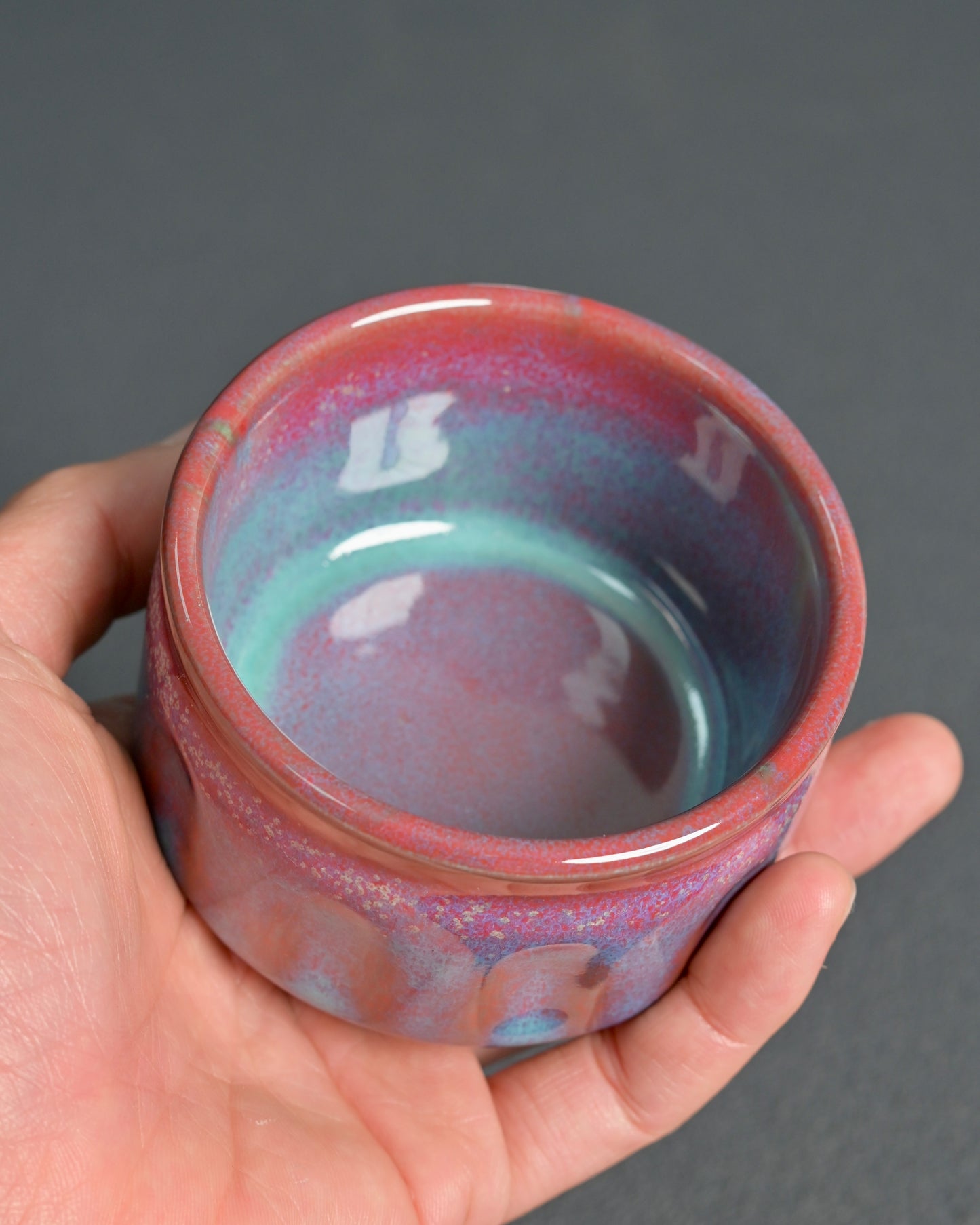 Copper-iron glaze flow patterns creating unique atmospheric colors through wood kiln firing