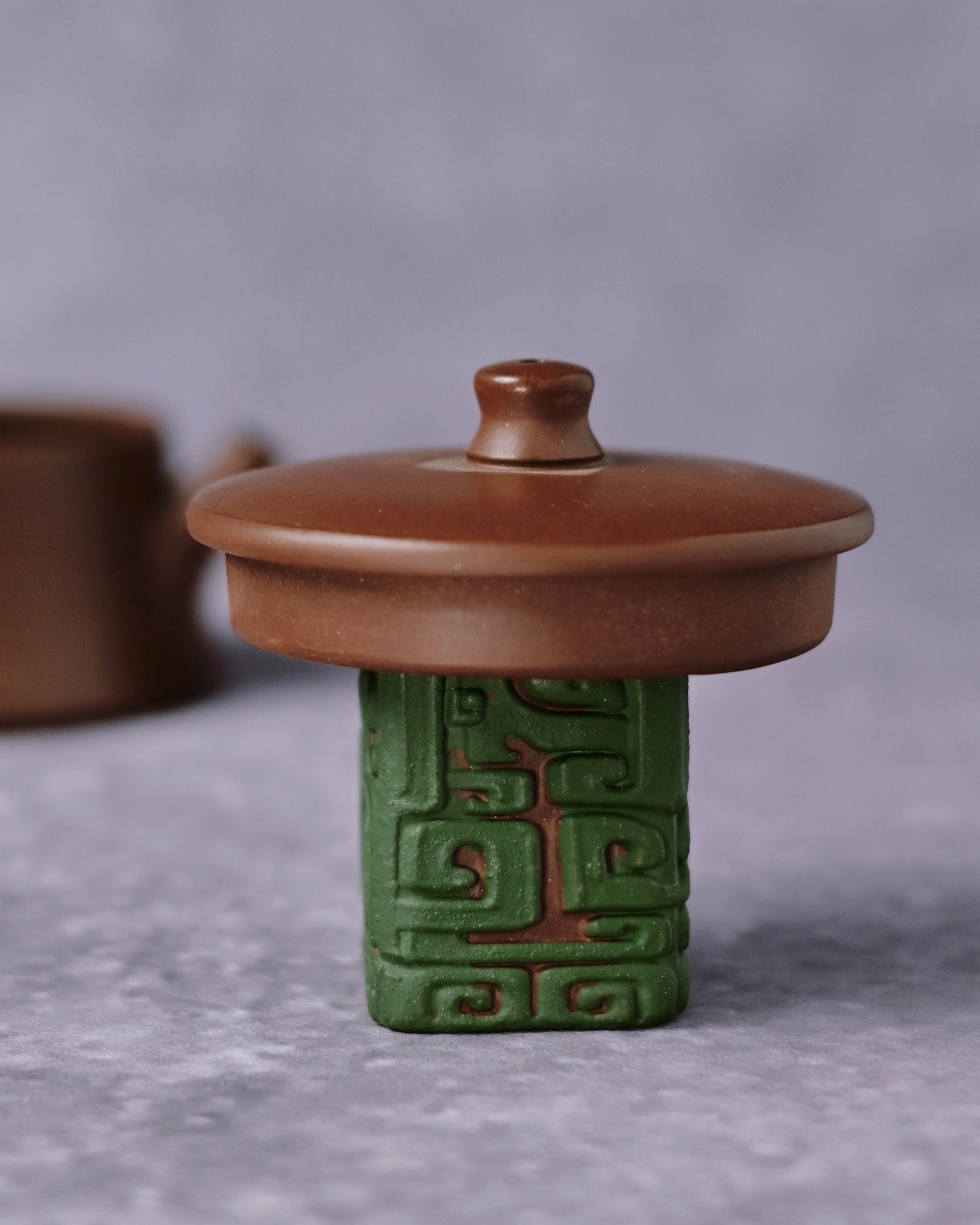 Dual-function lid holder and tea pet with flat platform top and four carved decorative panels