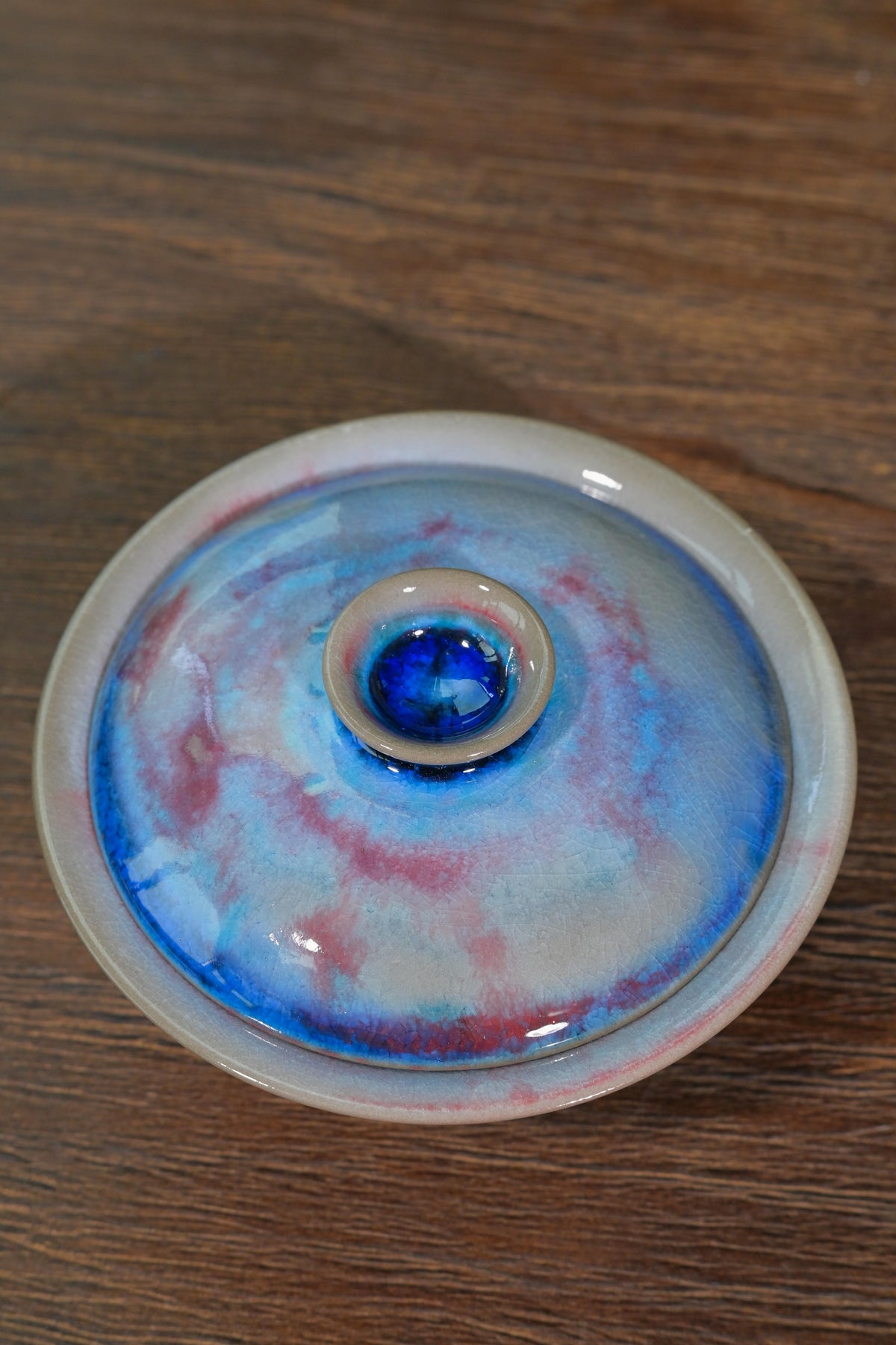 Chashao wood-fired gaiwan displaying electric cyan and magenta swirl on lid with unglazed foot ring