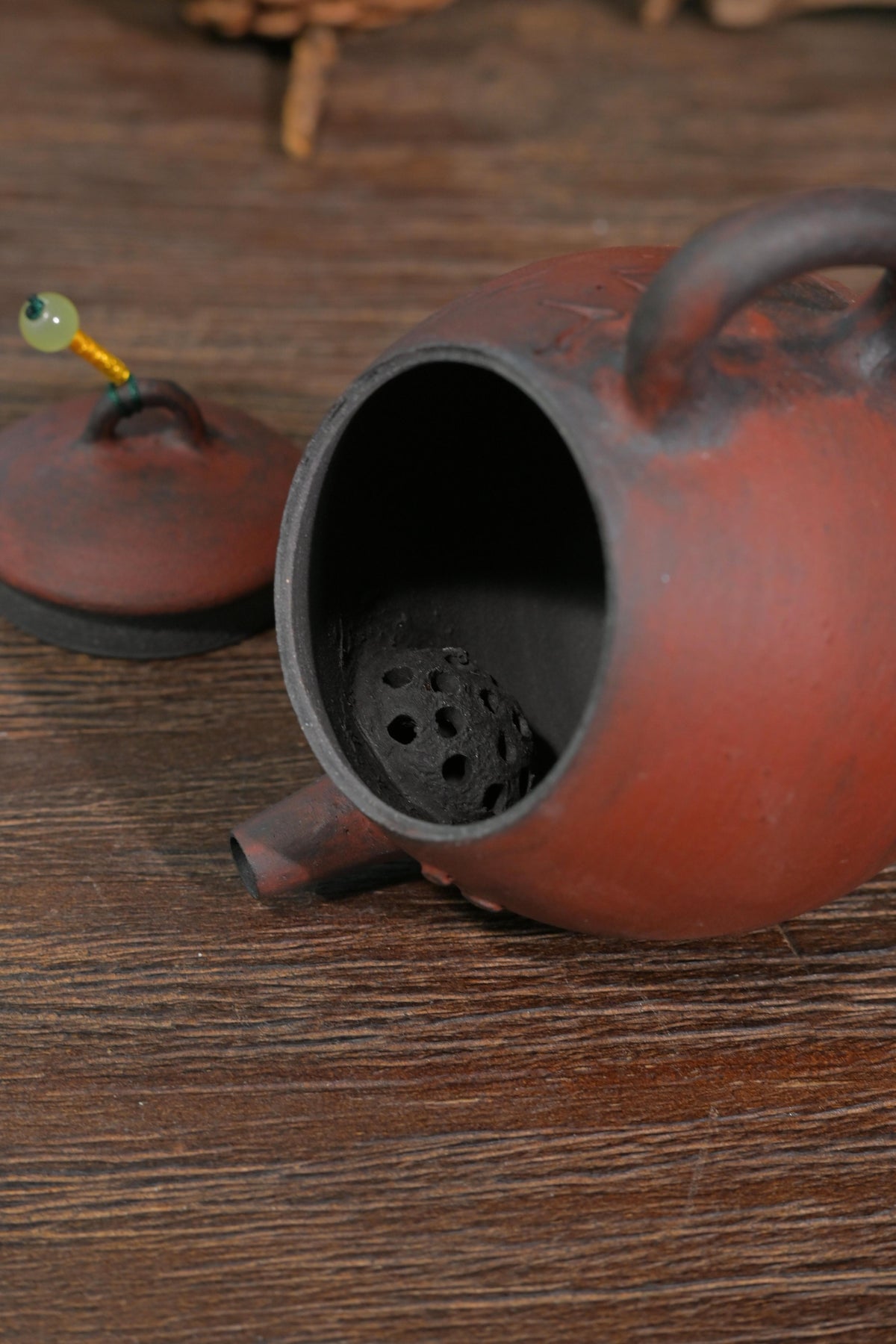 Traditional Chinese wood-fired scholar teapot with carved Chinese calligraphy set against dark reflective background