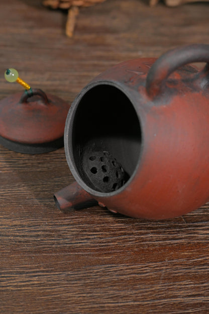 Traditional Chinese wood-fired scholar teapot with carved Chinese calligraphy set against dark reflective background