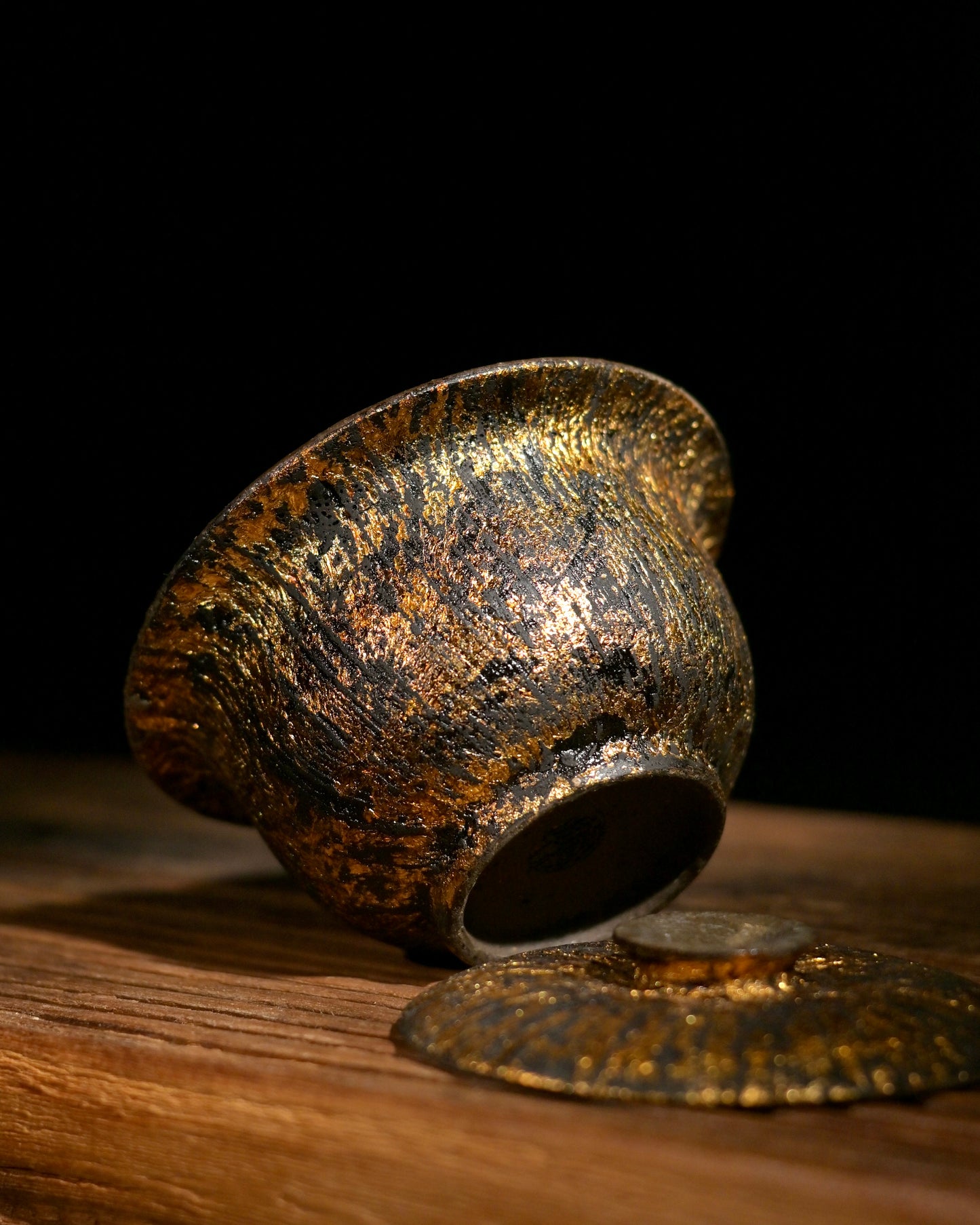 Macro shot of SAANWU raw lacquer gaiwan, vertical hand-drawn gold leaf texture on rough coarse clay body