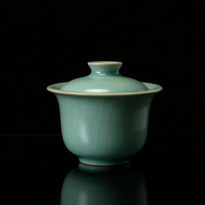 Hand holding Ru Ware sky-blue glazed Sancai ingot Gaiwan 110ml against black background   