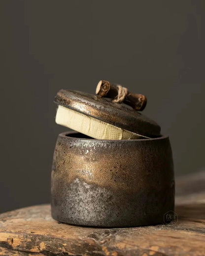 Side view of a vintage gilded stoneware tea container for loose leaf tea.