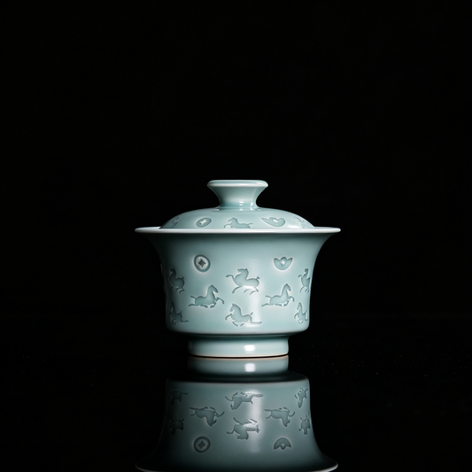 Traditional Chinese Longquan celadon lidded tea bowl with raised carved relief of horse and ancient coins