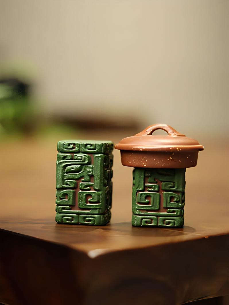 Four-sided beast motif holder with vermilion clay exposed in carved grooves against green slip surface