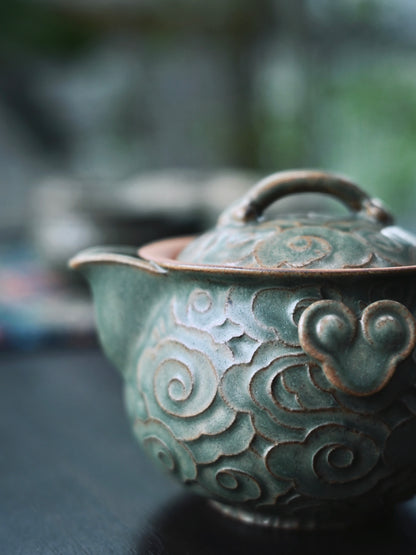 Hand-built purple clay (zisha) teapot with raised 'auspicious cloud' design, celadon glaze, and matching cups - a complete artisanal tea set.